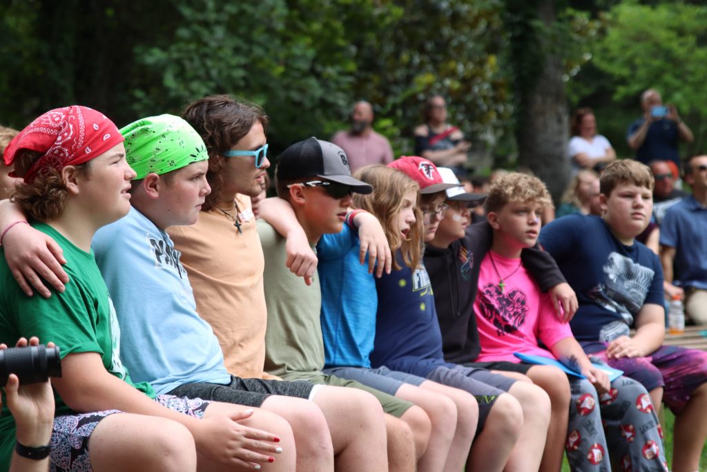 River Explorers campers sitting arm in arm on a bench at Lutheridge