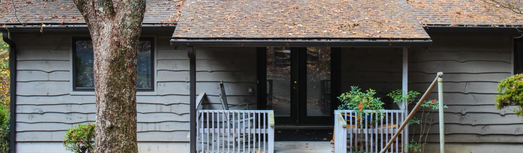 The front porch of the Bacot Center, a gray-sided house at Lutheridge with white railings