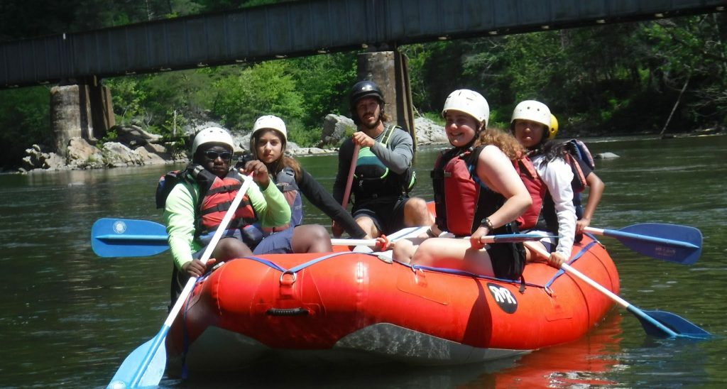 Campers and their guide paddling a raft on a river at Lutheridge