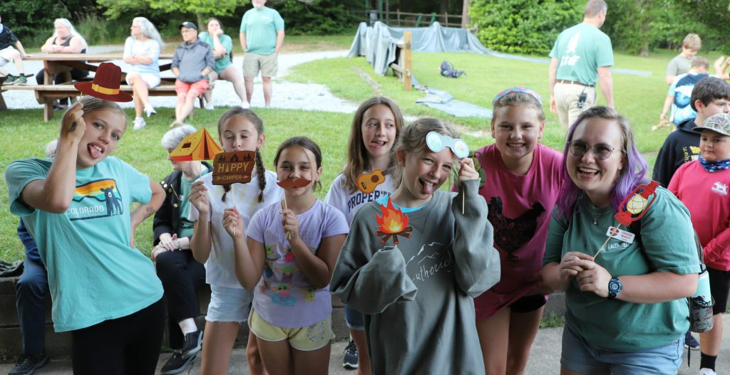 Campers and their counselor laughing with photo-booth props at Crazy Cool Campout at Lutheridge