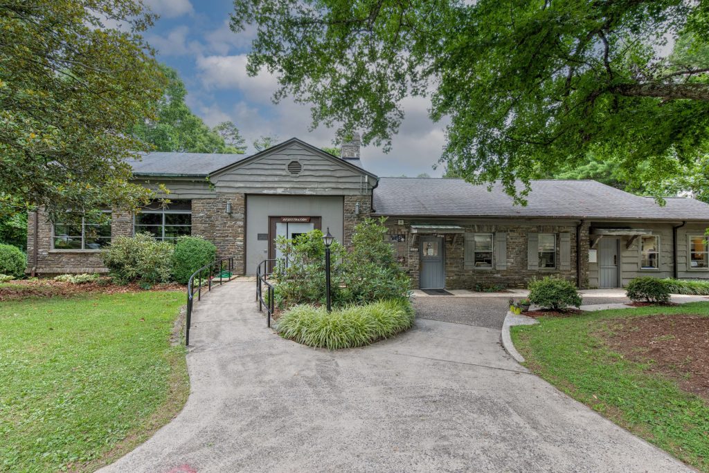 Efird Hall at Lutheridge, a stone building with a gray roof among gardens and walkways