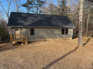 A gray Hill Cabin at Lutheridge with a wooden front deck among tall pines