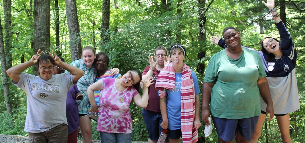 Summershine campers and their counselors make silly faces together in the woods at Lutheridge