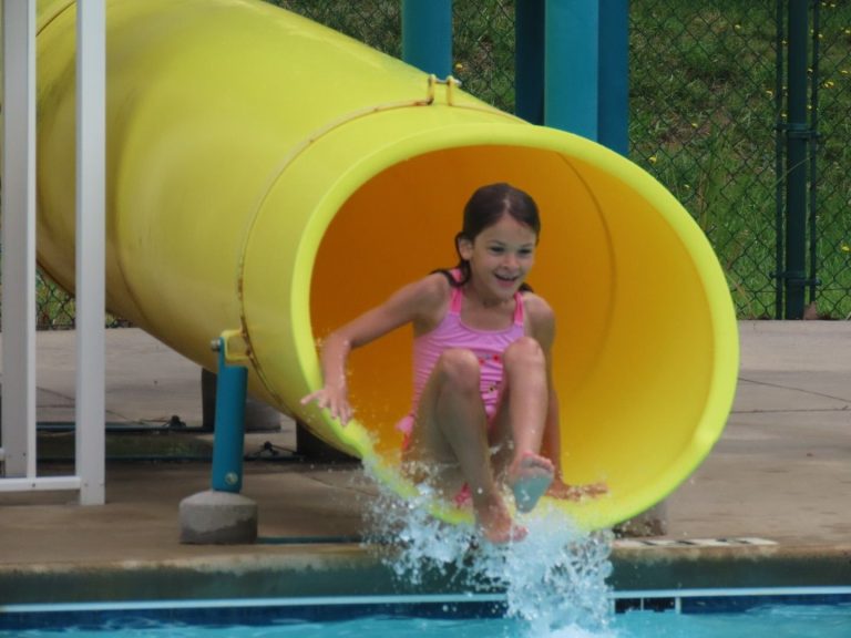 A young camper shooting out of the yellow water slide into the Lutheridge pool