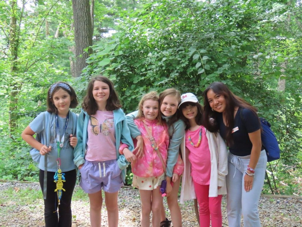 A Lutheridge cabin group of elementary-age campers smiling with their counselor in the woods