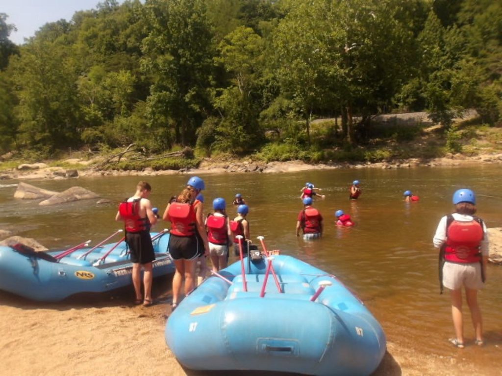 Rock & Raft campers in helmets and life jackets with their rafts at the river