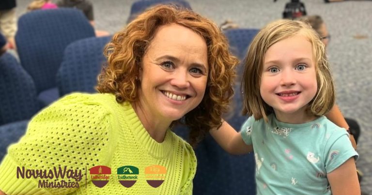 A woman and a young girl smile together in a church sanctuary