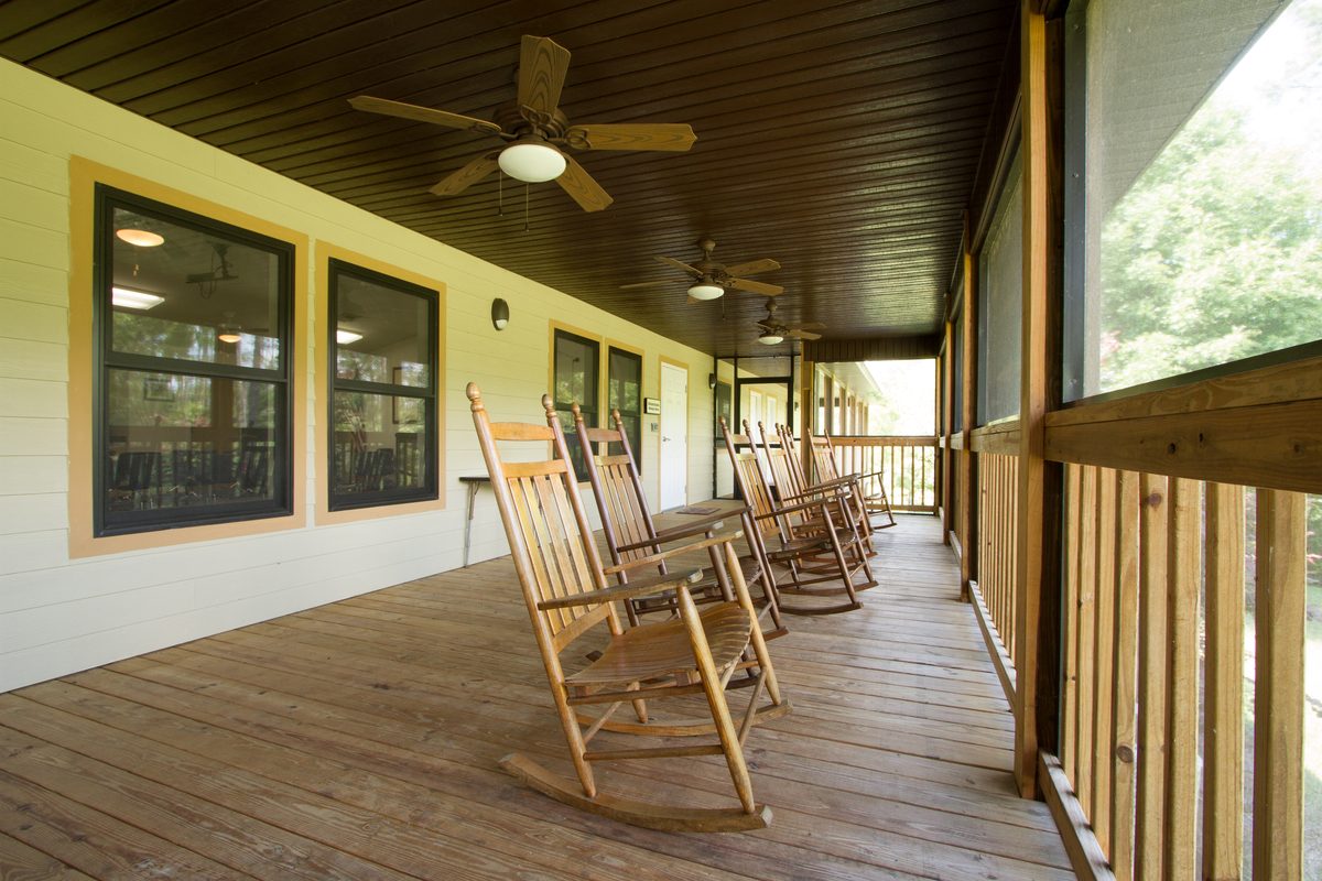 Rocking chairs lined up along a wide screened porch at Luther Springs