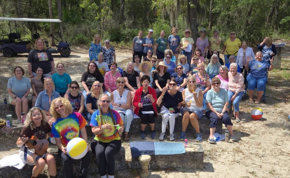 A large group of women smiling together outdoors on a retreat weekend at Luther Springs