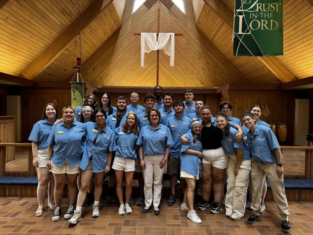 Luther Springs staff in matching blue shirts gathered together in the chapel under a Trust in the Lord banner