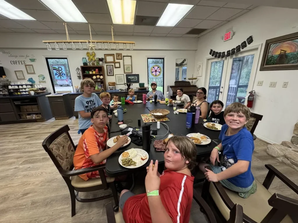 Young campers smiling around a dining table at Luther Springs