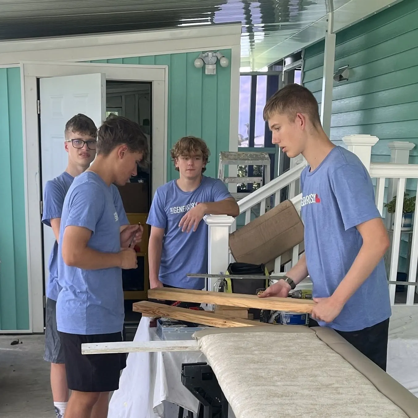 Teen volunteers measuring and cutting boards on a porch during a Luther Springs disaster response trip