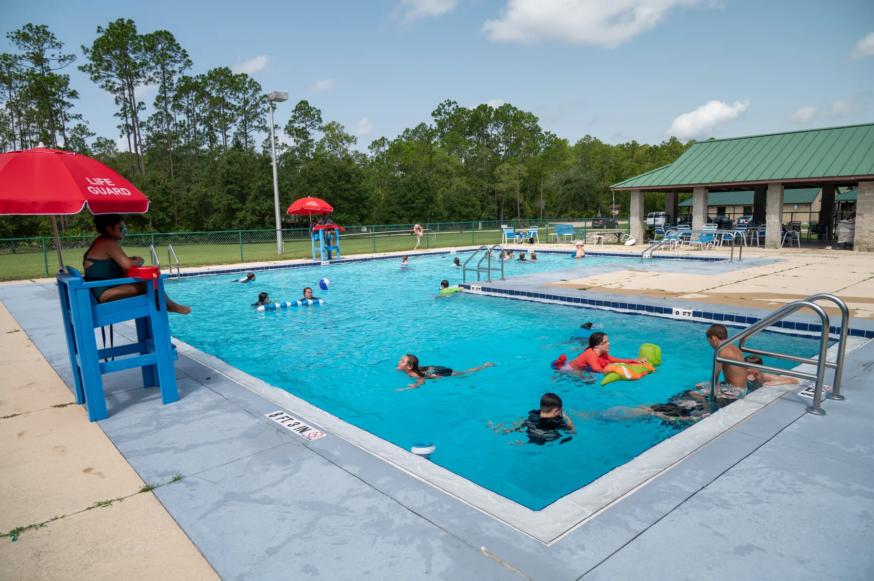 Campers swim and play in the Luther Springs pool while a lifeguard watches from the stand