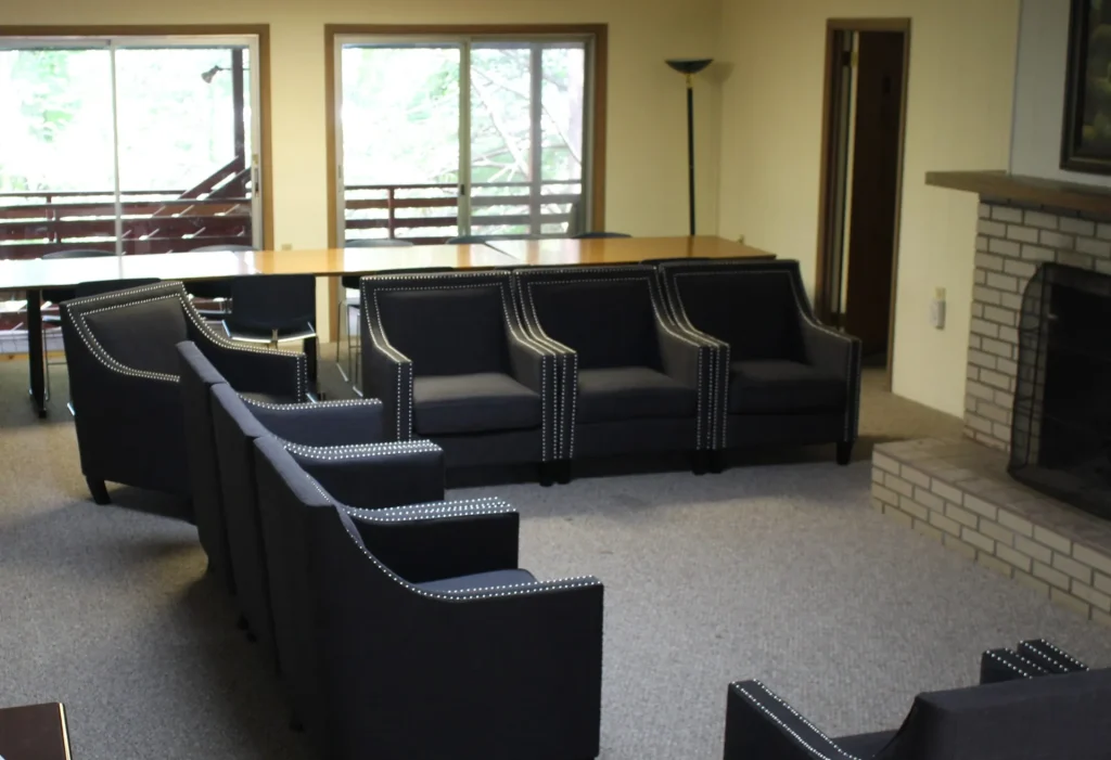 Bacot Center's gathering room: armchairs, a long table and a brick fireplace