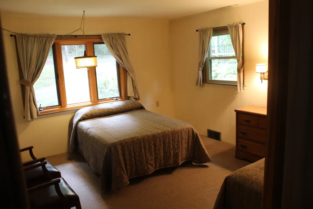 A Bacot Center bedroom with a double bed under two windows