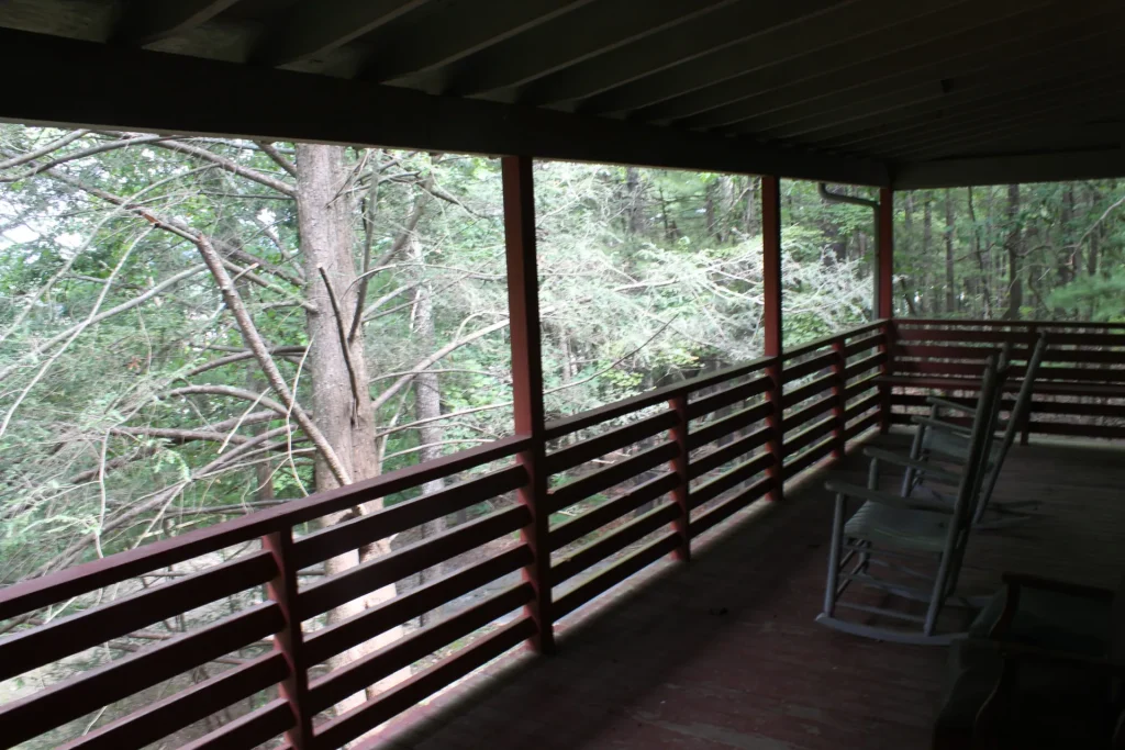Bacot Center's covered porch with rocking chairs, looking into the woods
