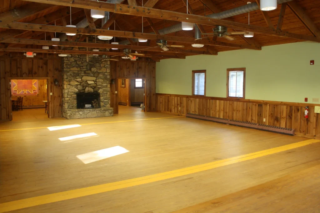 The Bischoff Center hall with a stone fireplace and sunlight on the wood floor