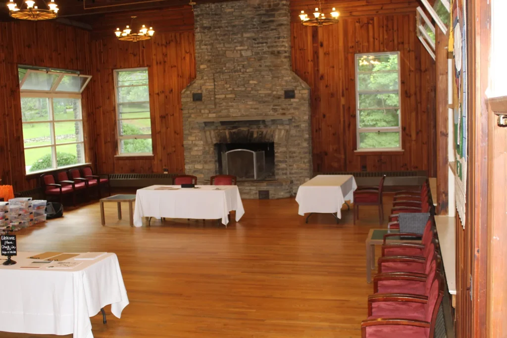 Efird Hall's main room: a stone fireplace, wood floor and tall windows