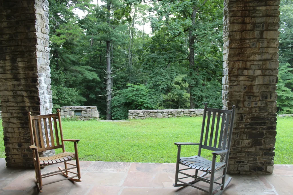 Rocking chairs between stone pillars, facing the Efird Hall lawn