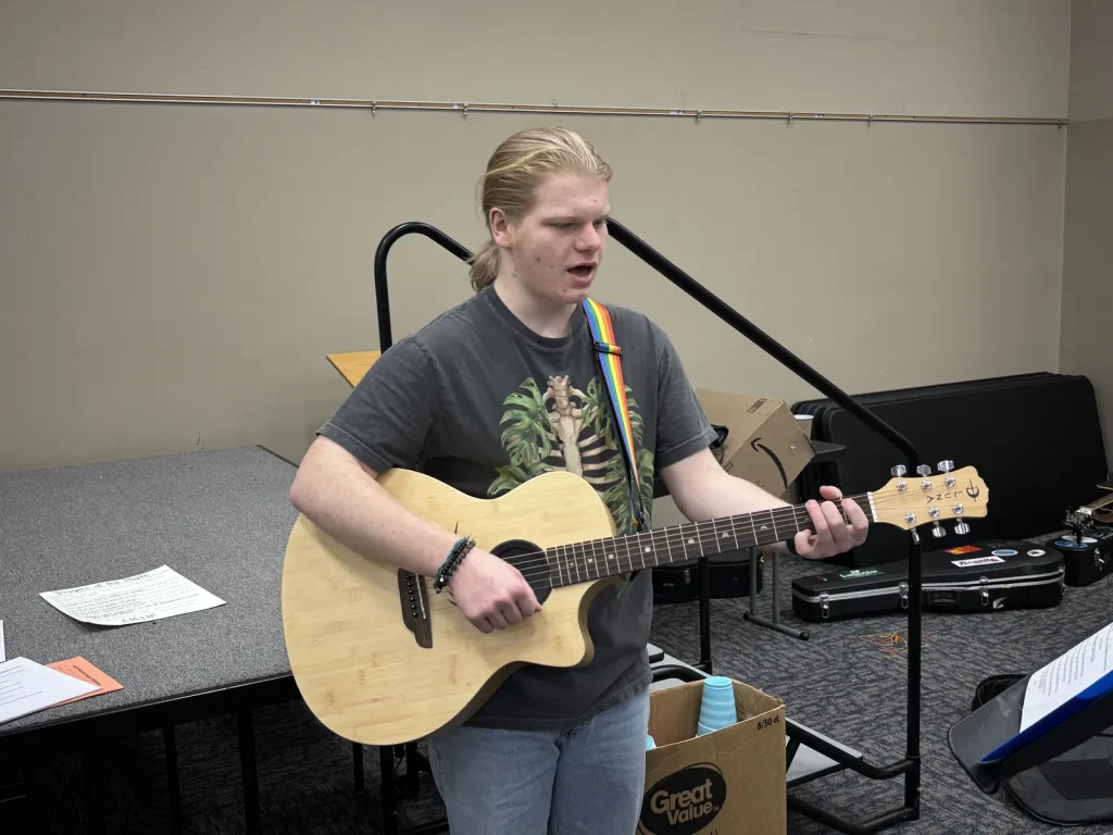 A young worship leader singing and playing acoustic guitar