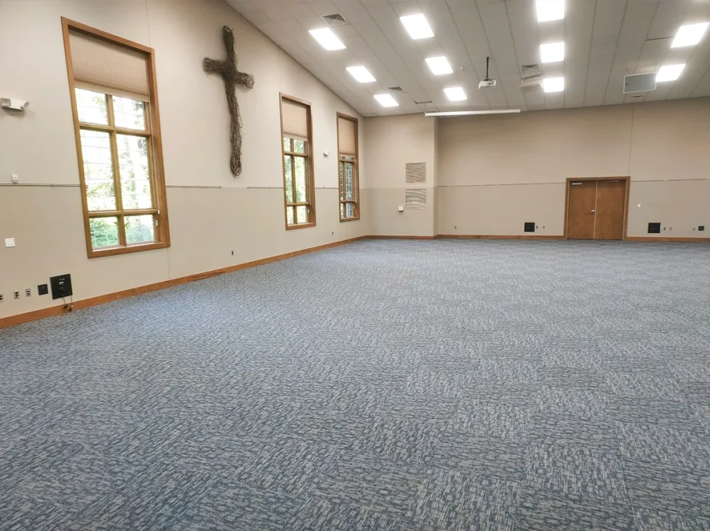 Faith Center's open hall with a cross on the wall and carpet throughout