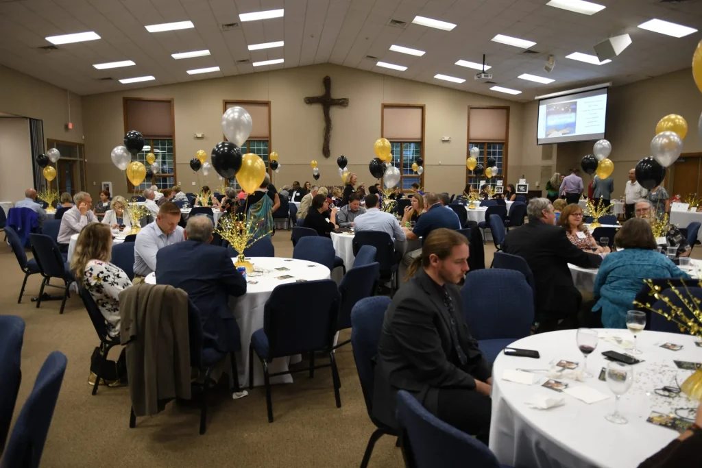 A banquet in the Faith Center hall, round tables decorated with balloons