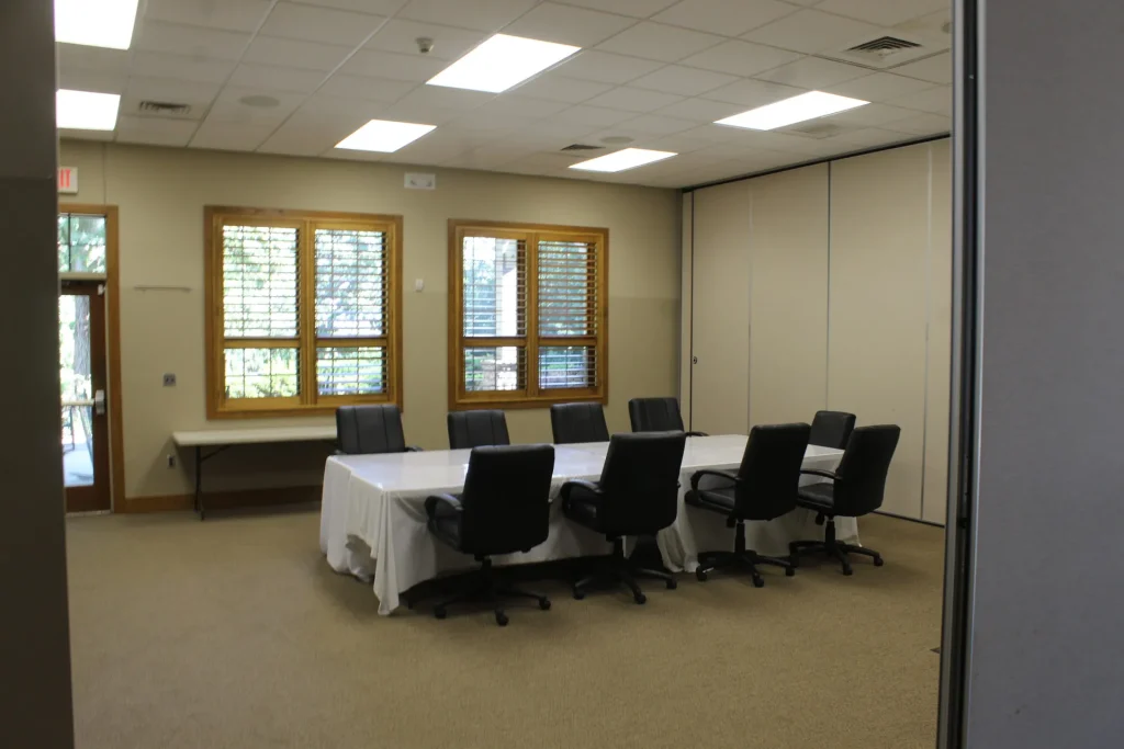 A Faith Center meeting room with a long table and office chairs
