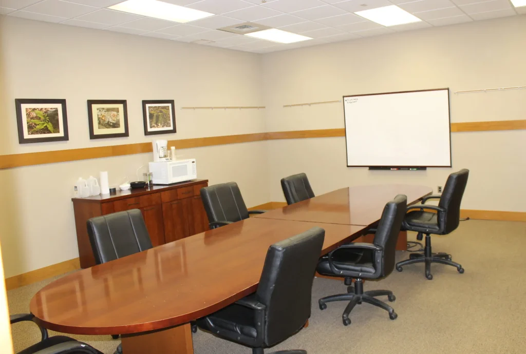A Faith Center conference room with a long wooden table and a whiteboard