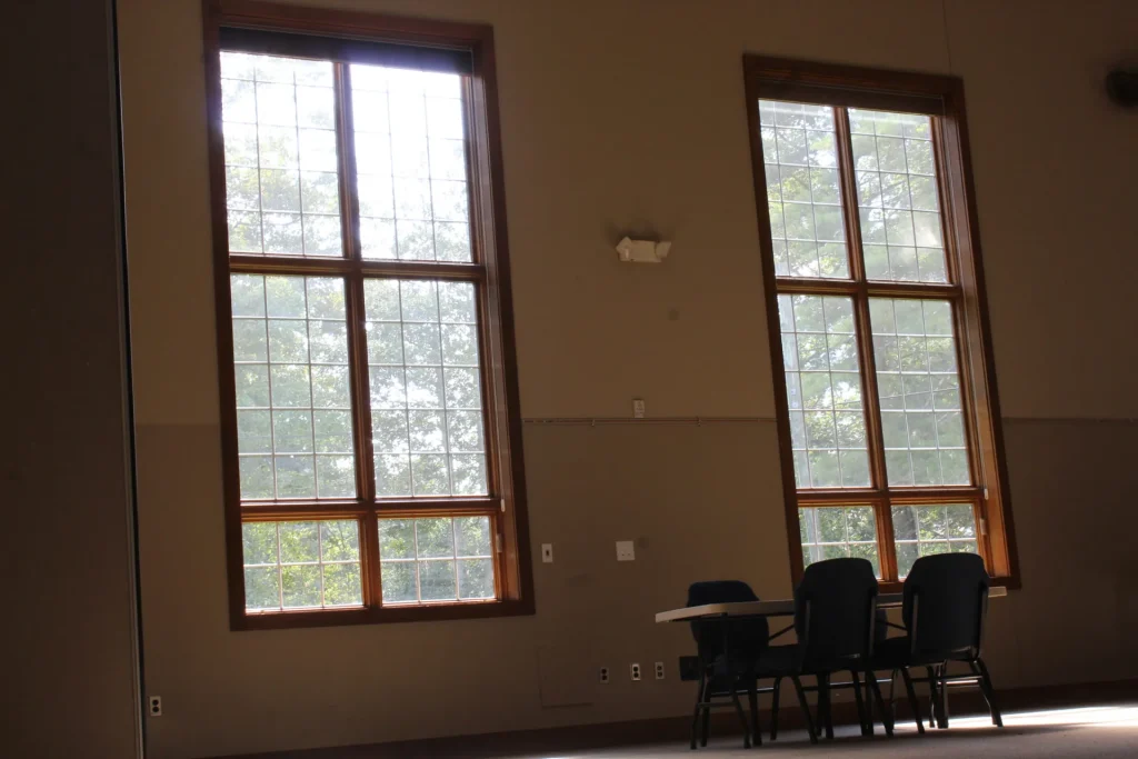 Tall windows in a Faith Center room, a small table set beneath them