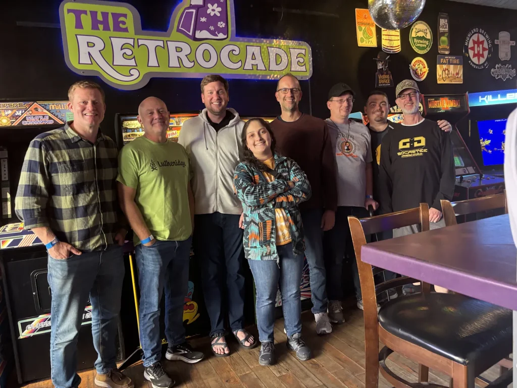 Geek Gathering guests posing together under the sign at The Retrocade arcade on the retreat outing