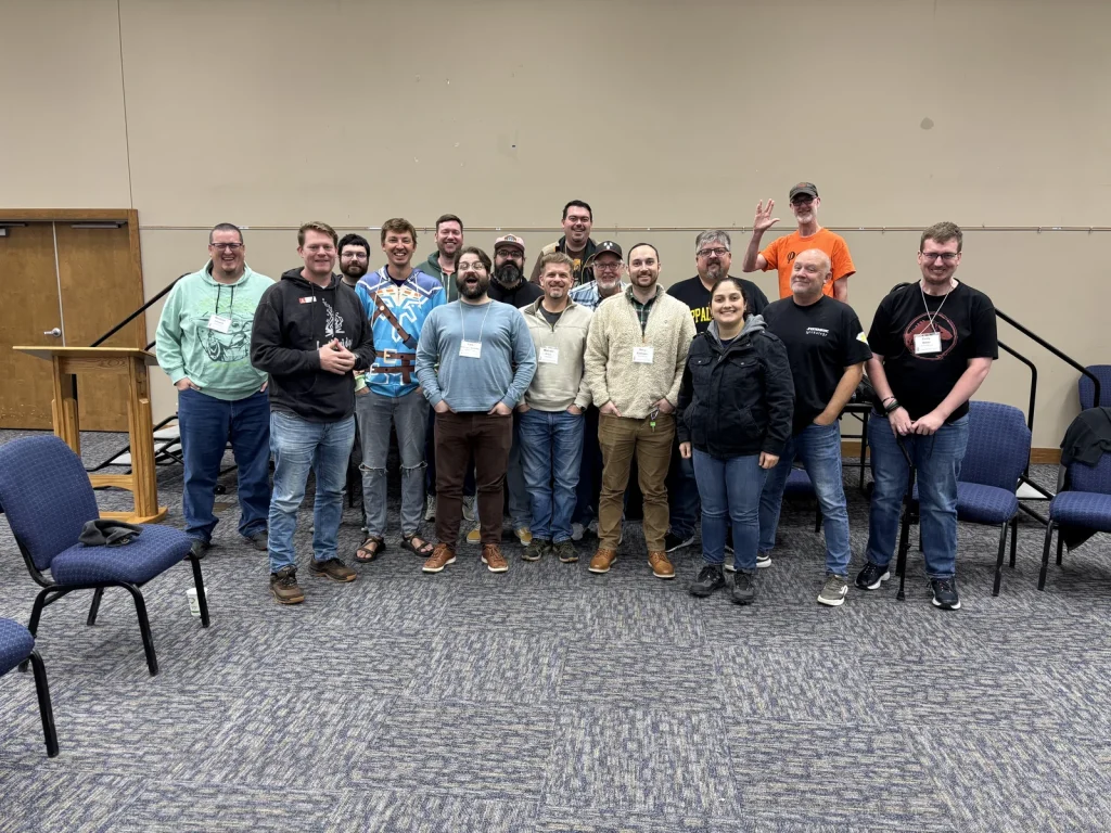 The Geek Gathering group in name badges posing together in a meeting hall