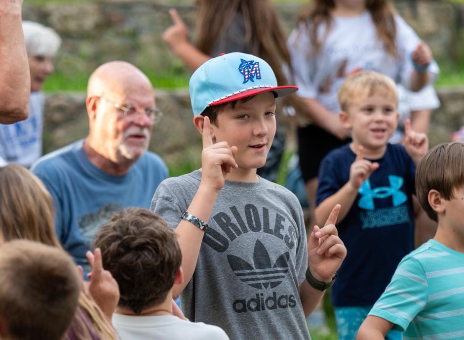 A grandfather and campers doing the hand motions to a song at Lutheridge Grands Camp