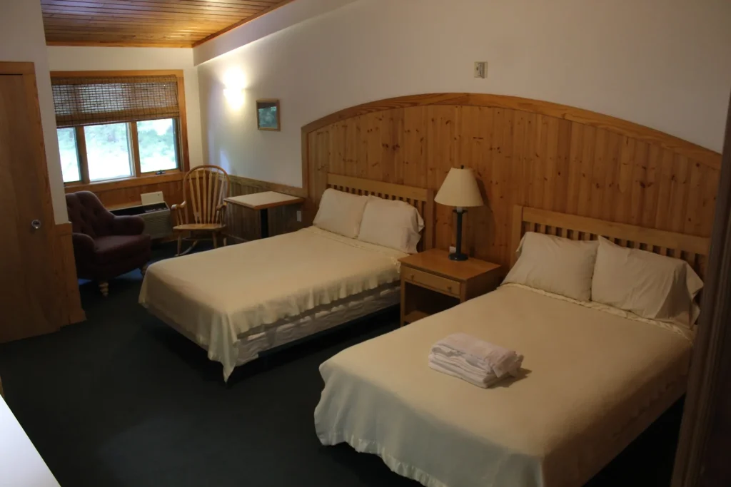 A Kohnjoy Inn guest room with two beds, an armchair and a desk