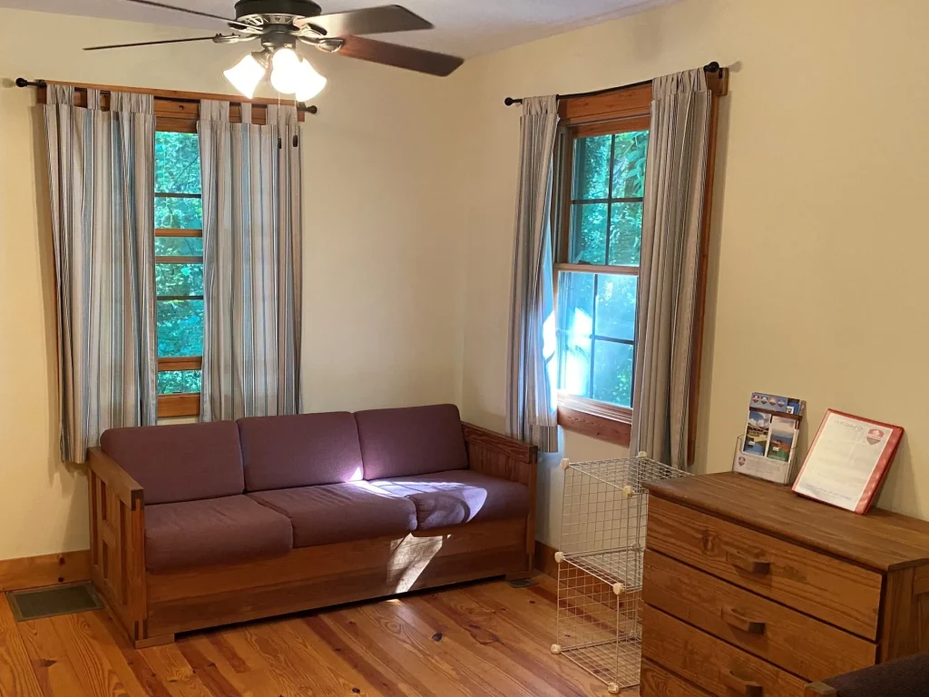 A Lakeside Village cabin sitting room: sofa, dresser and two windows