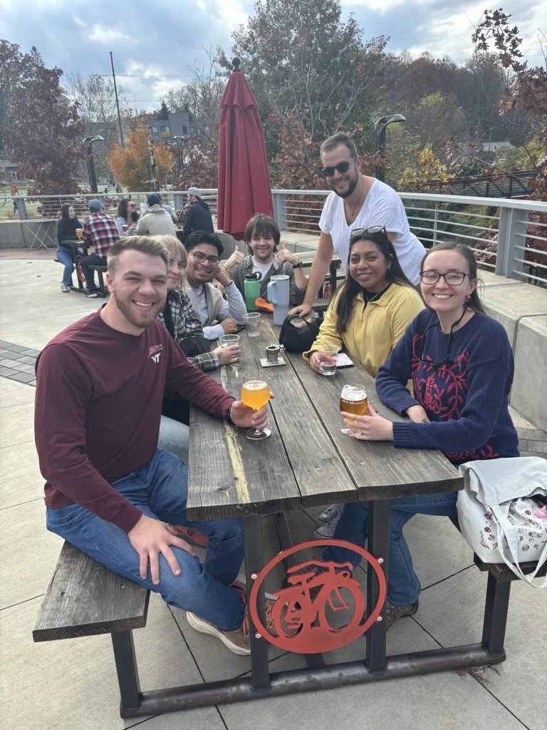 Theology On Tap guests at a picnic table on a brewery patio on a sunny fall afternoon