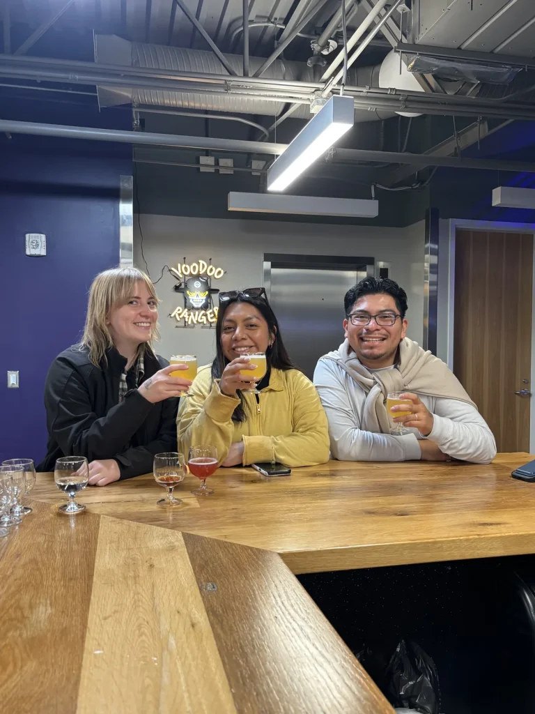 Three Theology On Tap guests raising tasting glasses at a brewery bar