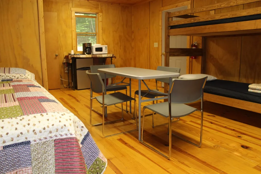 A table and chairs between the beds in a Cabin Village cabin