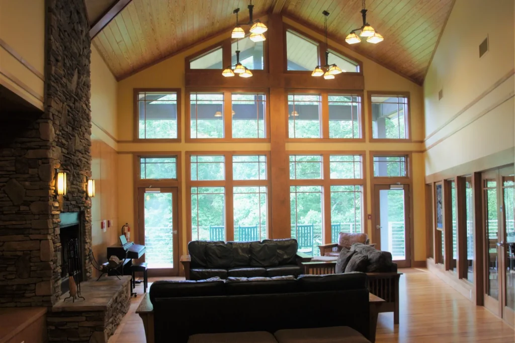 Crow's Nest's great room: tall windows, a vaulted ceiling and a stone fireplace