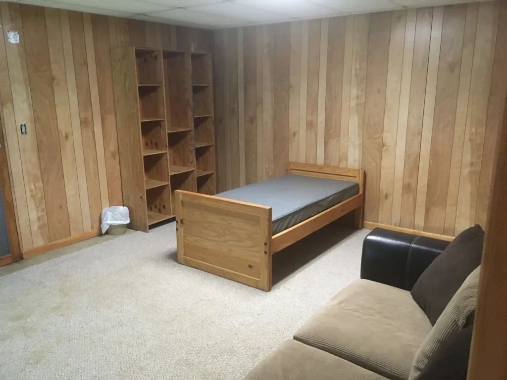 A Founders Lodge bedroom with a bed, shelves and a sofa