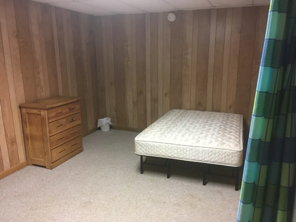 A Founders Lodge bedroom with a bed and a dresser