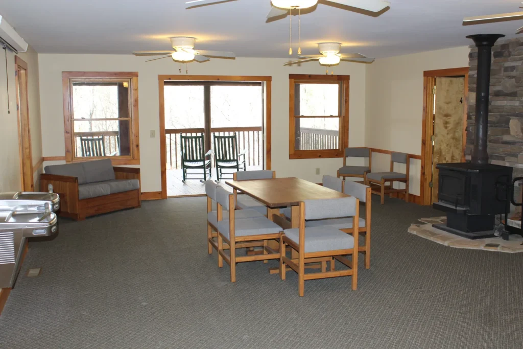 Moretz Cabin's living room: a wood stove, dining table and a door to the porch