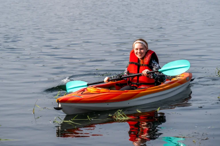 A camper smiling in a red kayak out on the water at Luther Springs