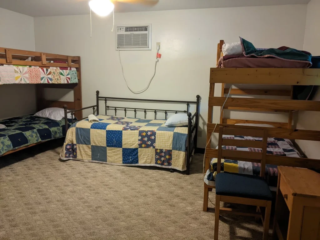 A Kuehner bedroom with bunk beds and a quilted double bed