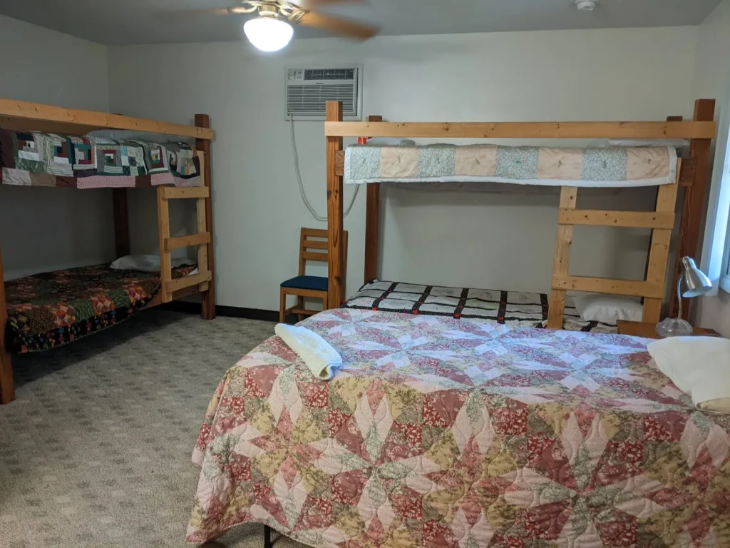 A Kuehner bedroom with a bunk bed over a double and a quilted bed