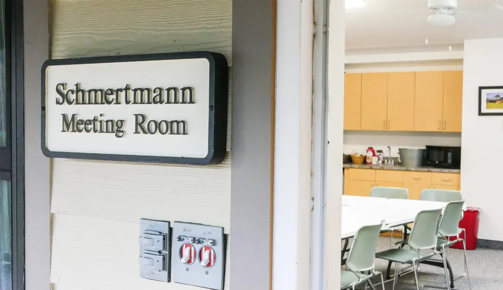 The Schmertmann Meeting Room door, with tables and a kitchenette inside