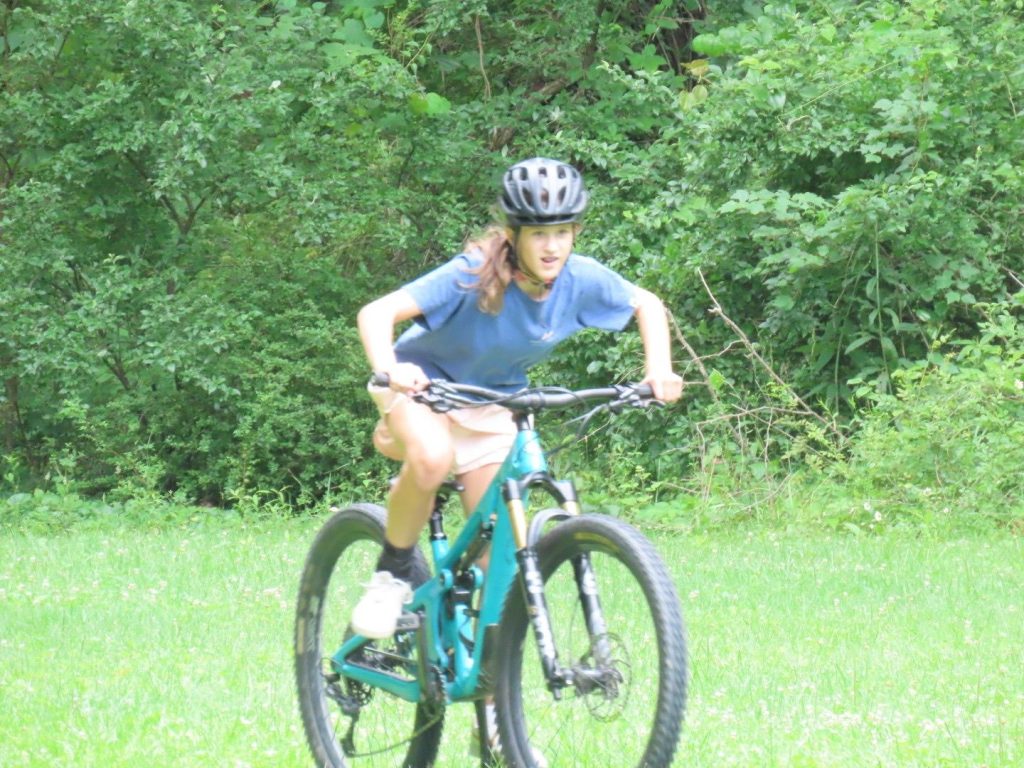 A camper in a helmet riding a mountain bike across the field
