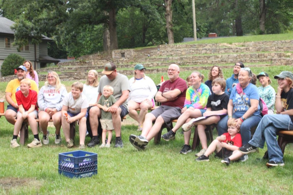 Families laughing together on benches on the lawn at Lutheridge Family Camp