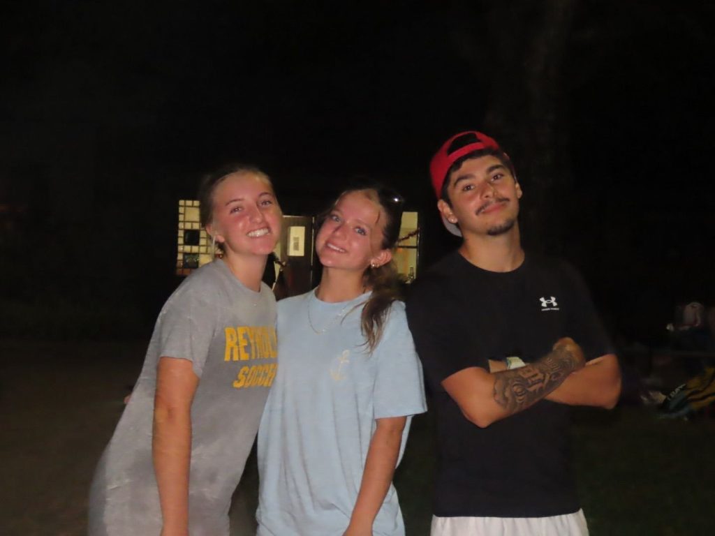 Three Night Owl campers smiling together outside at night