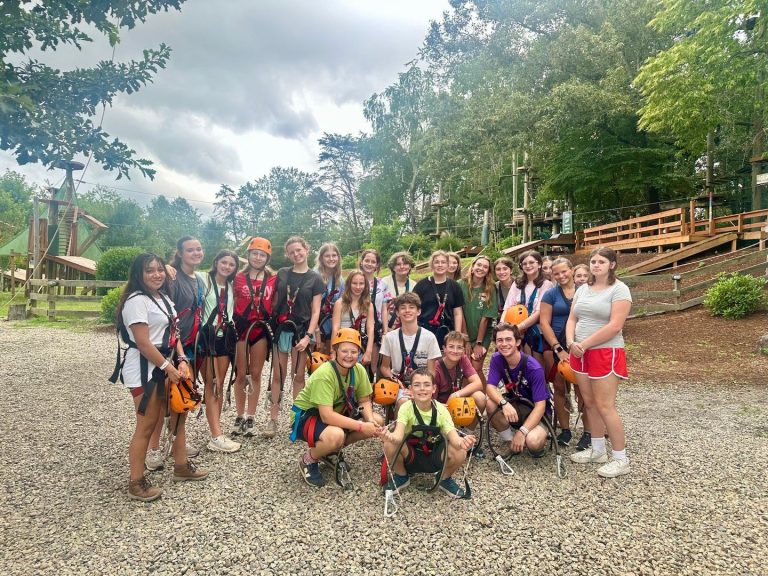 Sky Explorers campers in harnesses and orange helmets at the high ropes course