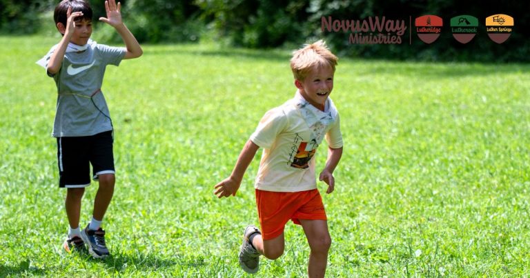 Two boys run and play on a sunny grassy field